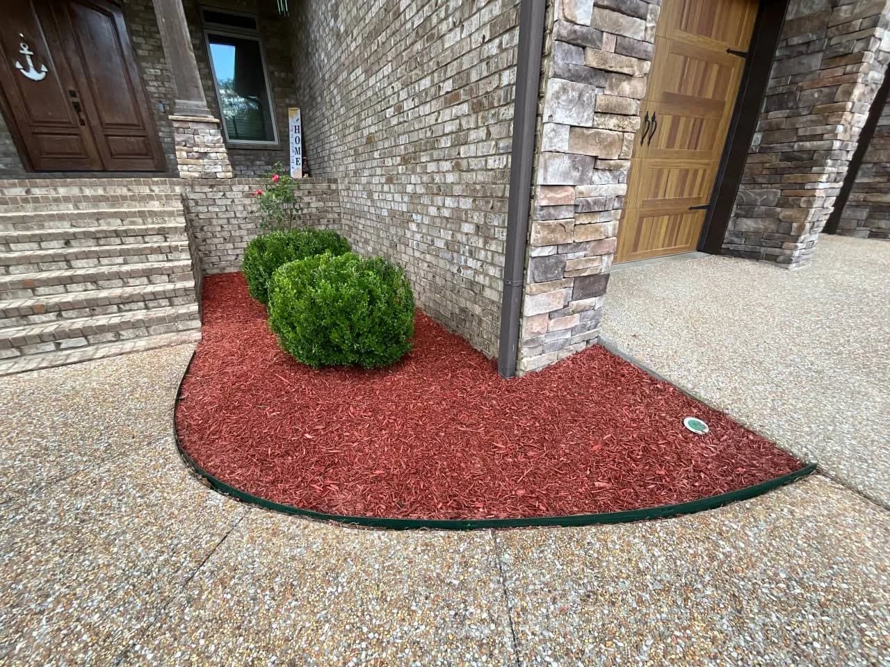 Fresh red mulch and clipped shrubs beside an entry walkway