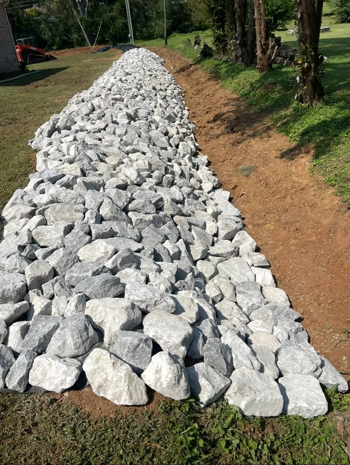 A stone-lined channel running through a sloped yard